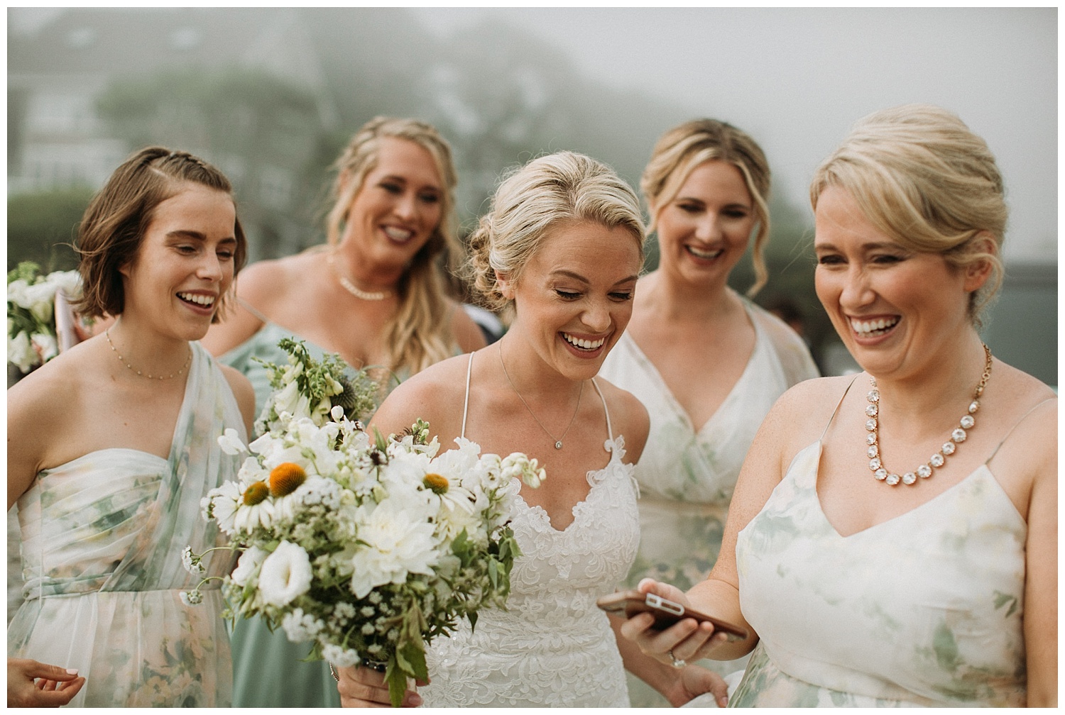 a bride laughs with her bridesmaids on the beach