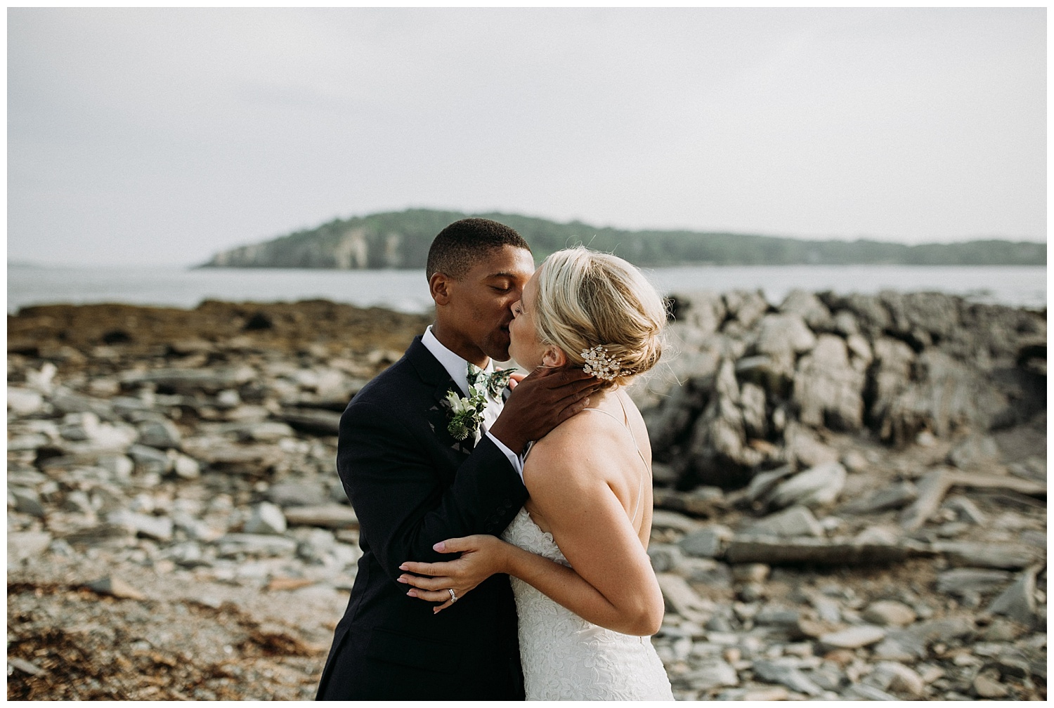 a bride and groom kiss on a rocky Maine beach