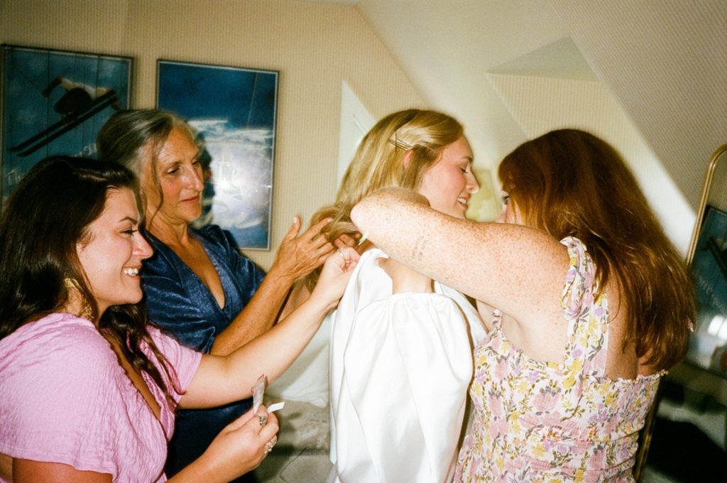a bride's friends helping her into her wedding dress