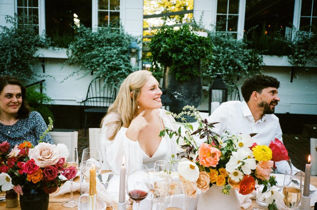 a couple sits at their colorful table setting on their wedding day