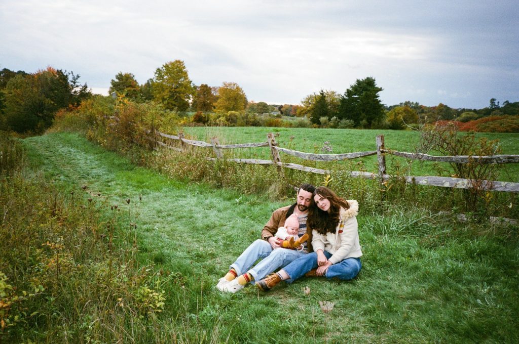 a family sits in a field in Massachusetts during a portrait session