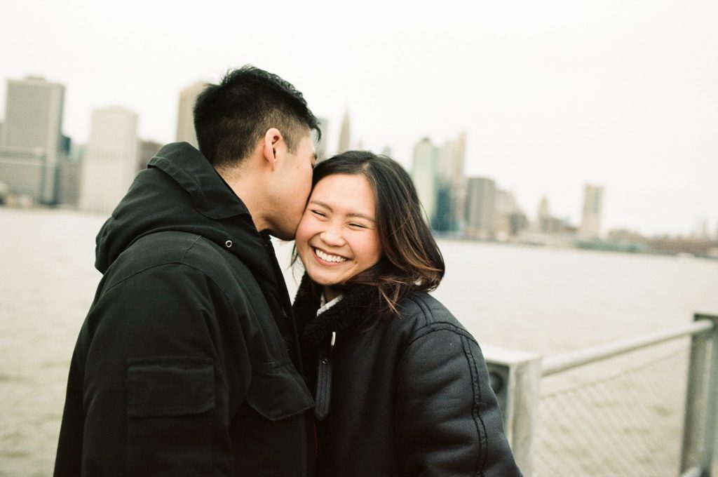 Loving couple cuddles in front of New York City skyline
