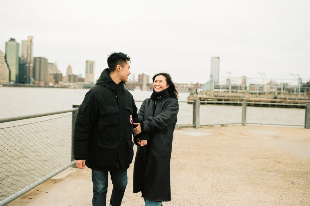 New York City couple smiles together along the Hudson River