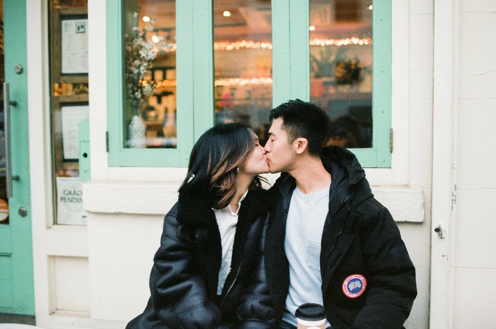 A Brooklyn couple share a kiss in front of a coffee shop