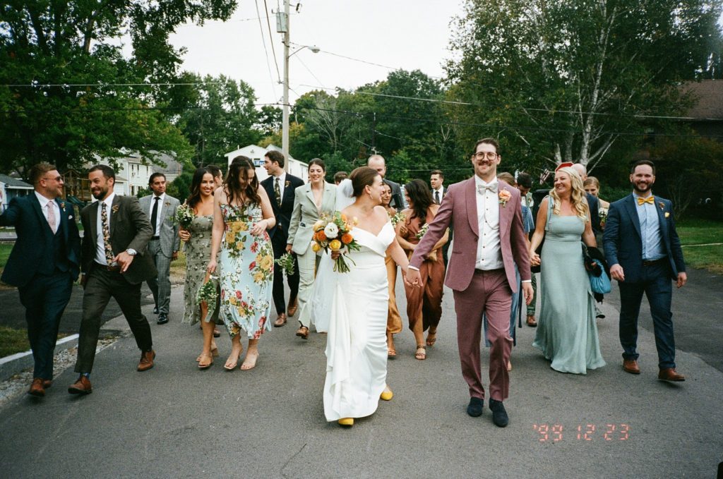 Film photo of modern wedding party walking from ceremony to reception