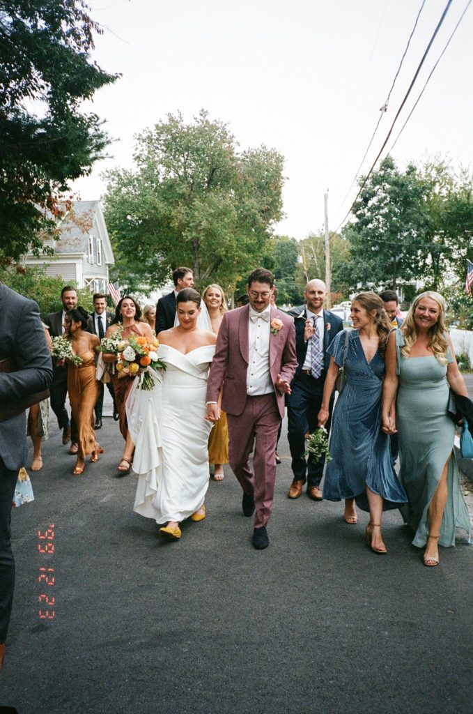Wedding party walks down New England street in the fall