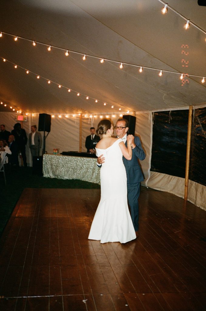Bride and father share a dance in a beautifully lit event tent
