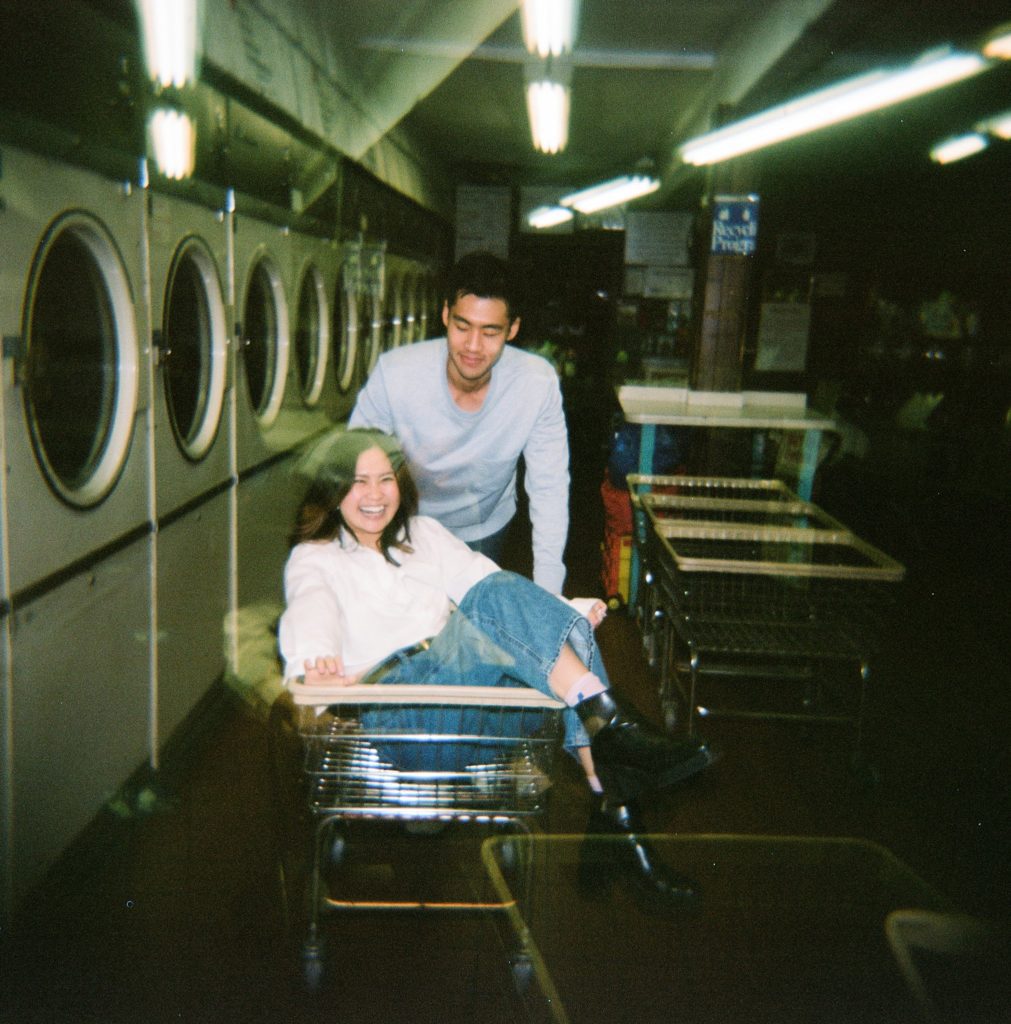 Film photo with motion blur of couple being silly together in a laundromat