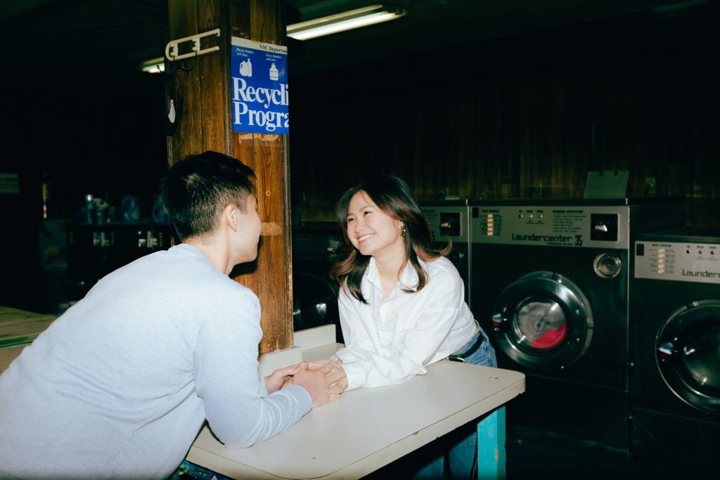 Woman smiles at her fiance inside a vintage New York City laundromat