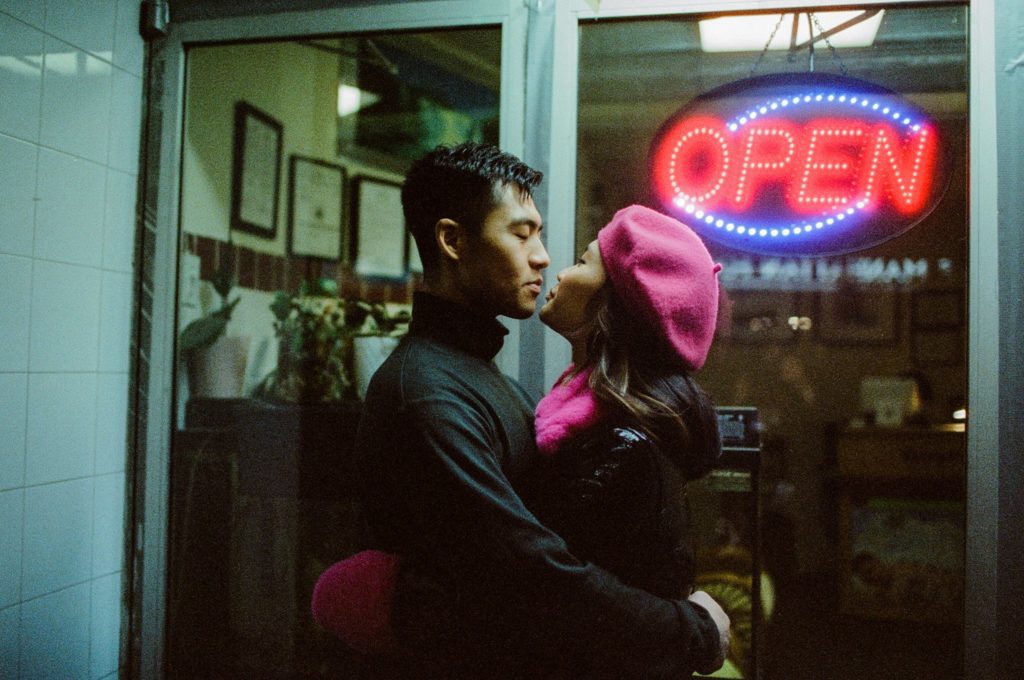 Profile film photo of couple embracing outside NYC storefront
