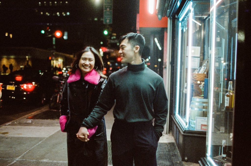 Couple laughs while walking at night in Brooklyn