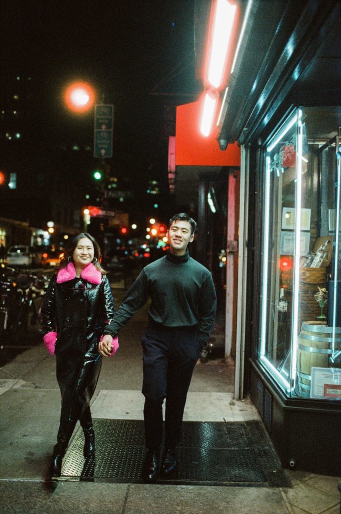 New York City couple walks down the street at night holding hands