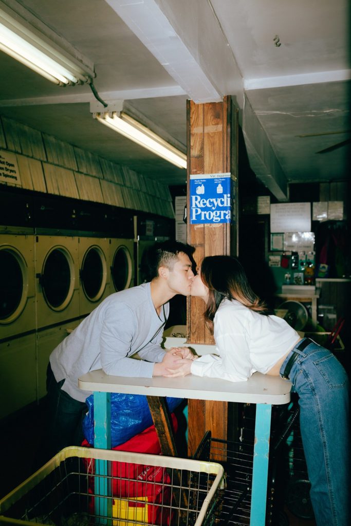 Brooklyn couple kisses over table in vintage laundromat