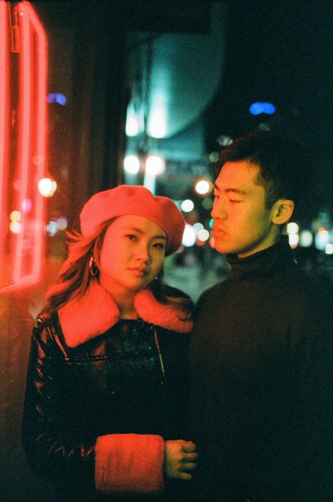 Red neon illuminated portrait of engaged couple captured on film
