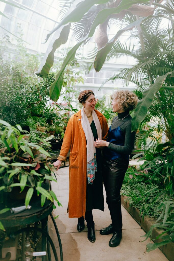 A couple looks at each other lovingly among lush plants in a Western Massachusetts greenhouse