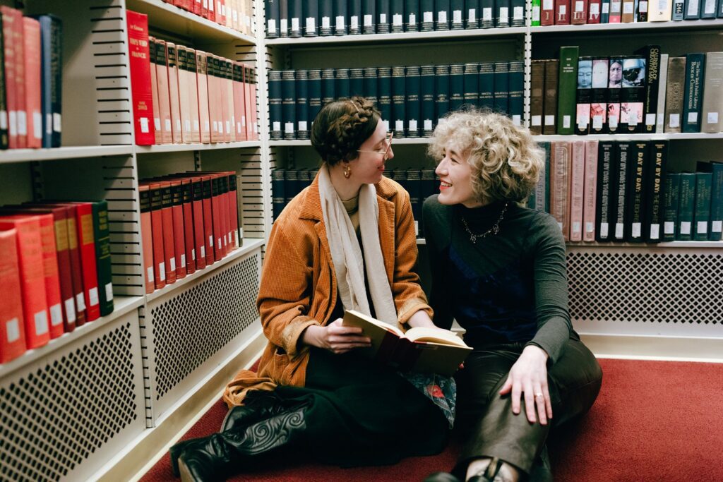 Two women smile together among books, captured on 35mm film