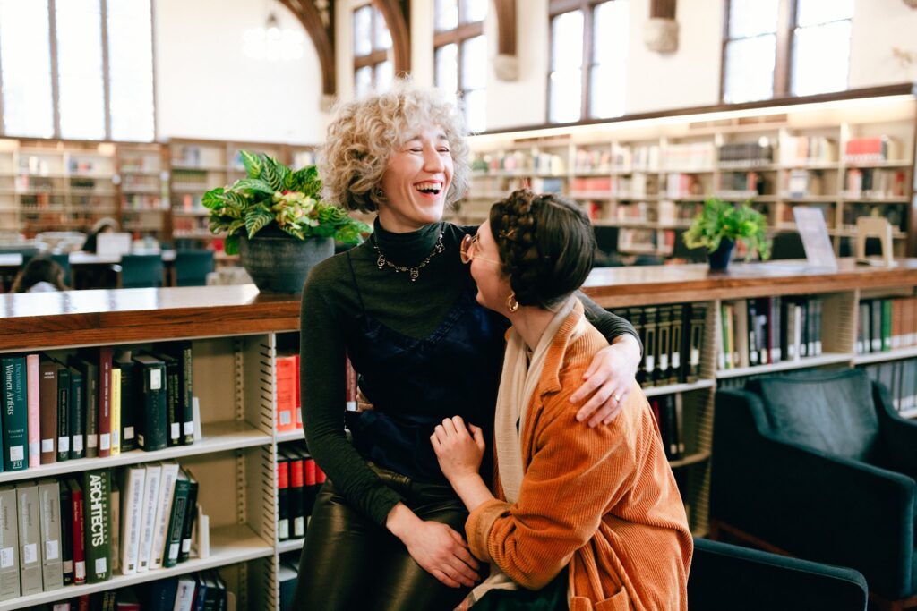 Engaged couple share laughter in brightly lit Berkshires library, captured on 35mm film