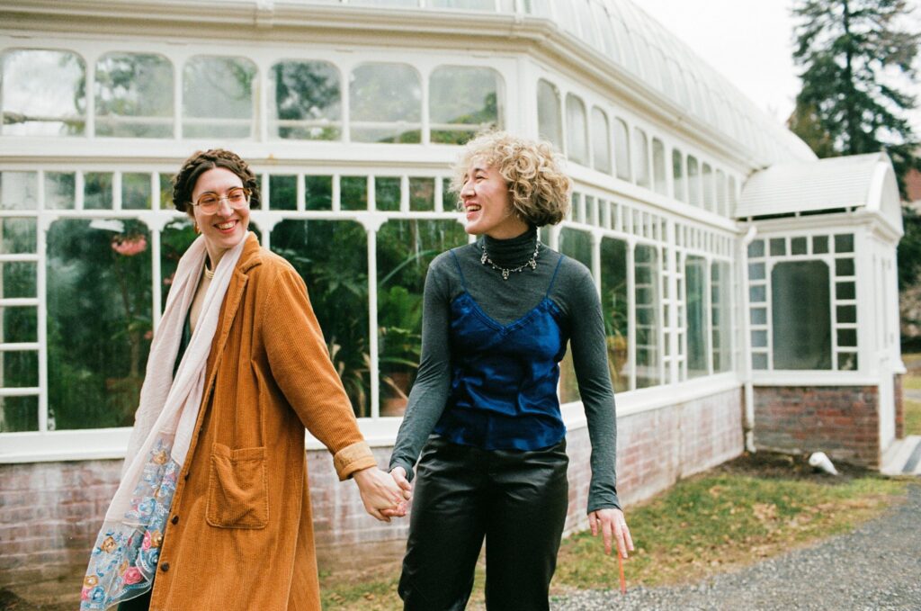 Two women hold hands, walk, and laugh together in the Berkshire Mountains