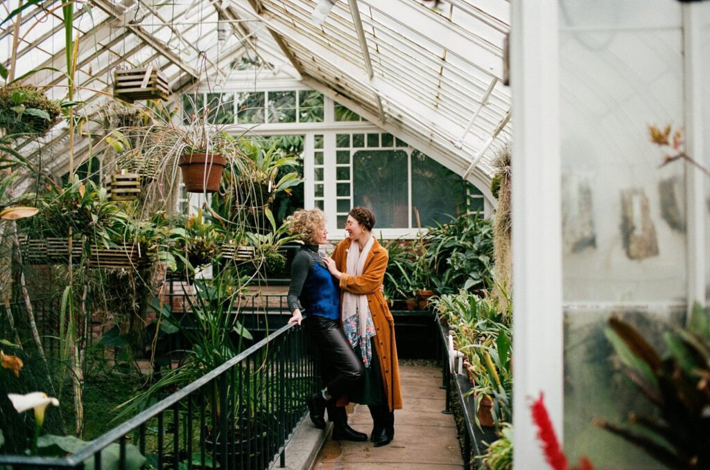 Two women celebrate their engagement inside Berkshires greenhouse surrounded by plants
