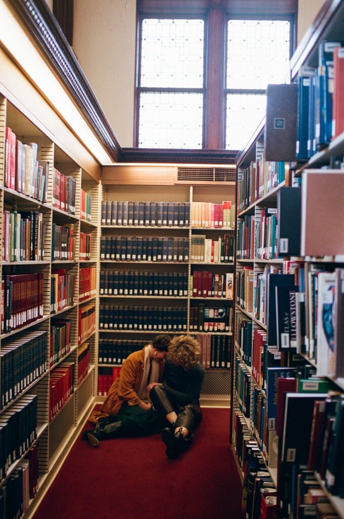 Engaged couple sit on the floor of a library together