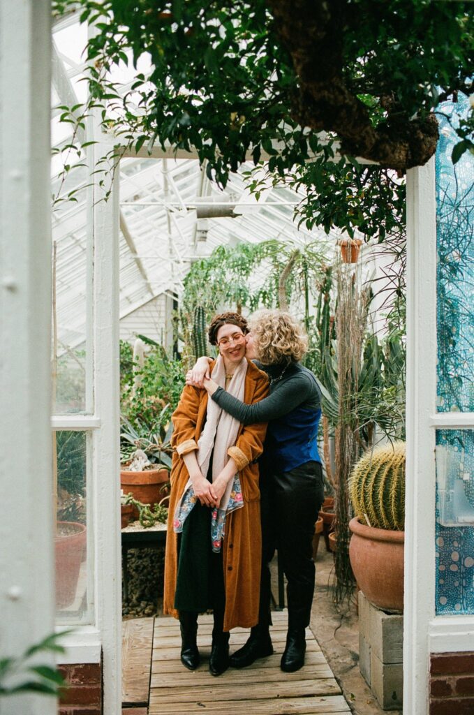 Massachusetts same sex couple embraces inside a greenhouse entryway