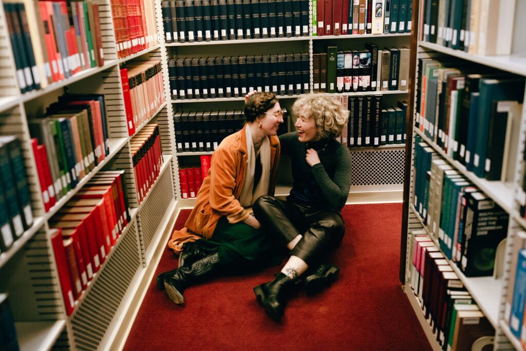 Engaged couple laughs together on the floor of a Massachusetts library