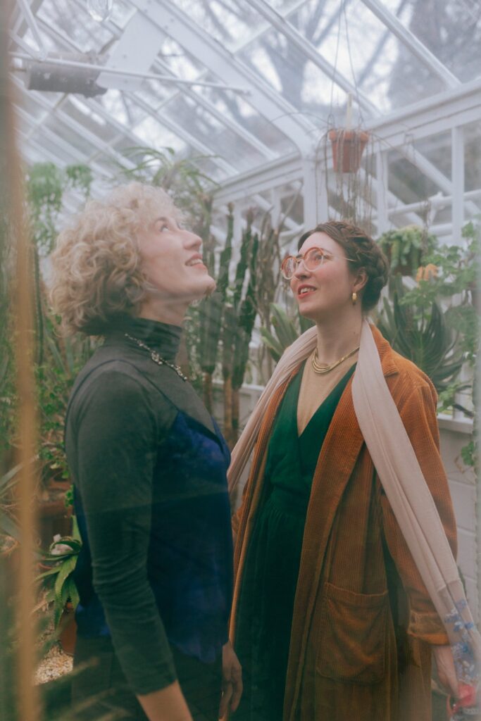 Film portrait of same sex engaged couple looking up through a greenhouse