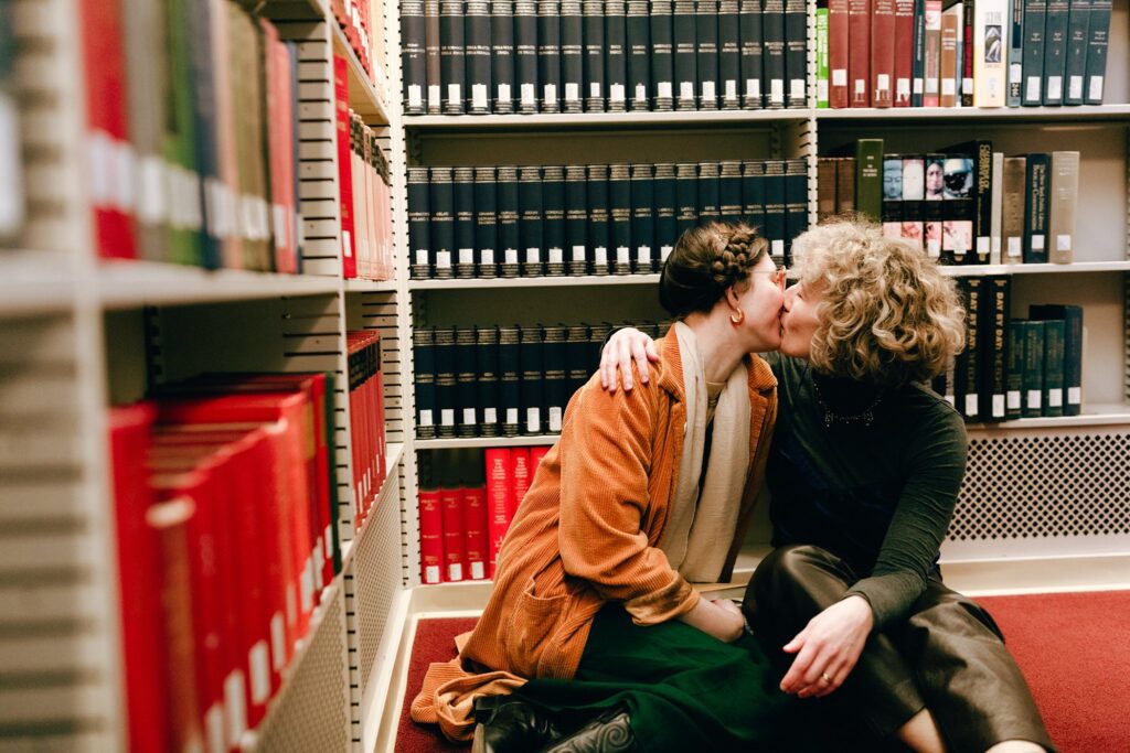 Engaged couple shares a kiss on the floor of a library