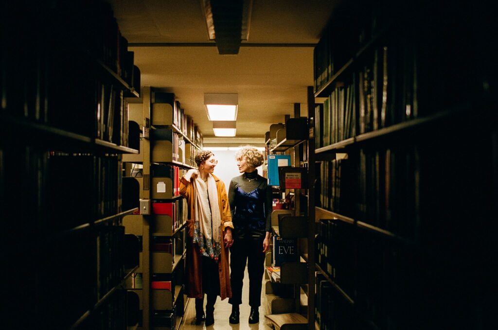 Two women hold hands together in the basement of a library