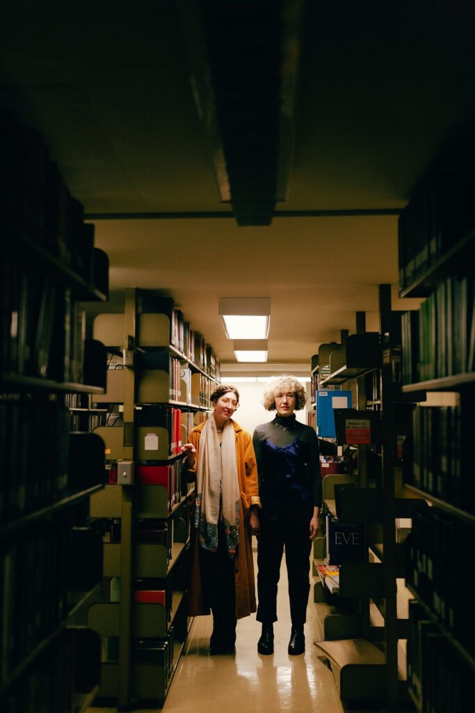 Film photograph of engaged couple posing among library book shelves