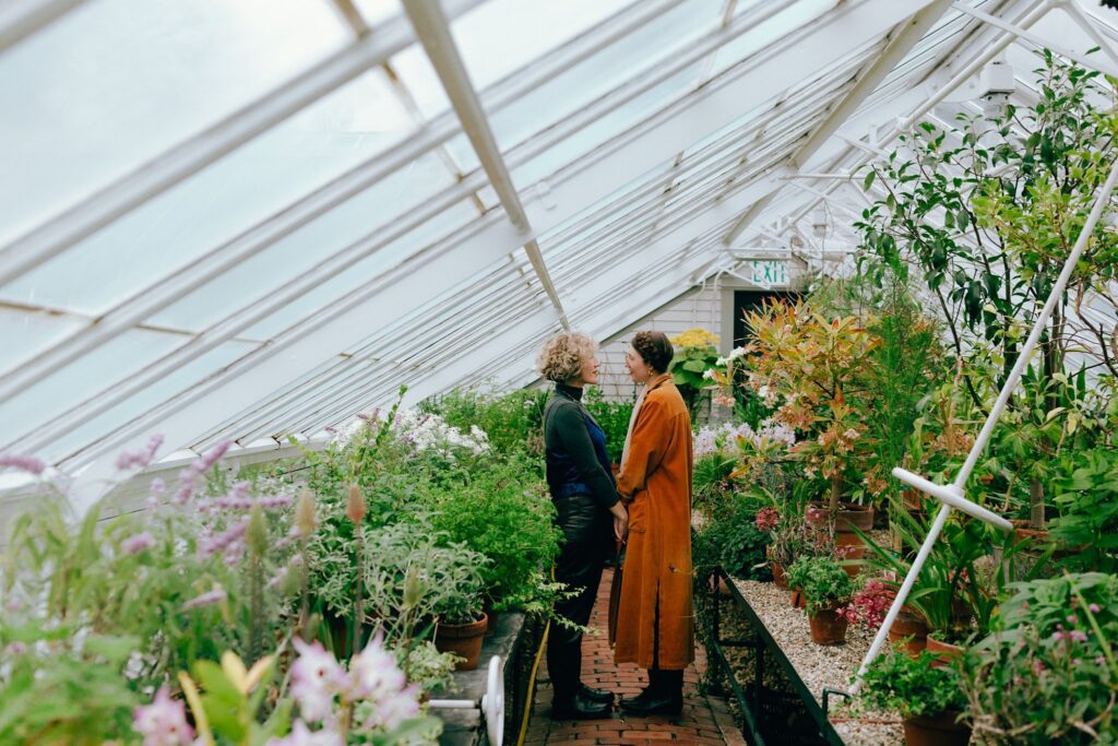 Portrait of engaged couple facing each other standing in the aisle of a greenhouse