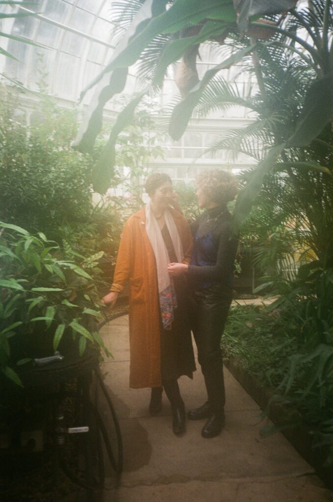 35mm film photo of engaged couple standing together inside Berkshires greenhouse