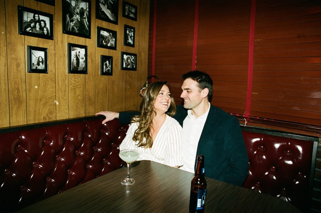 Boston couple smiles together in a booth in seaport bar