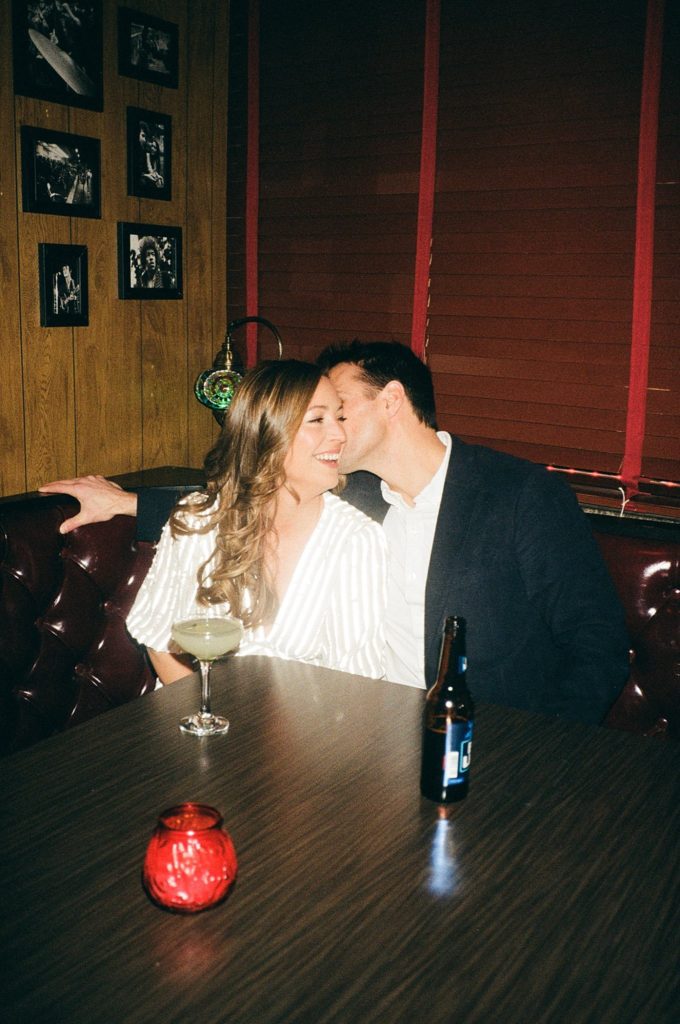 Woman laughs while her future husband kisses her in a Boston bar