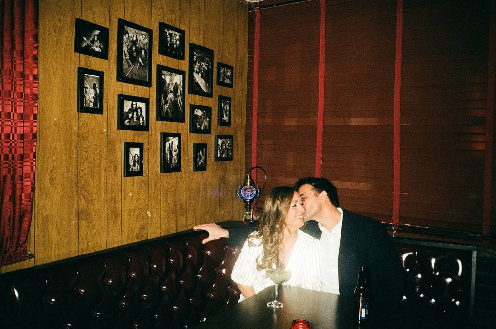 Direct flash photograph of engaged couple sitting together in a booth