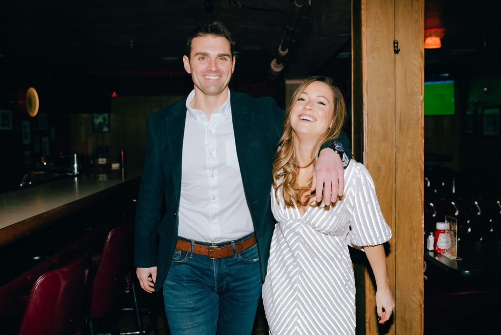 Film portrait of engaged New England couple smiling inside their favorite bar