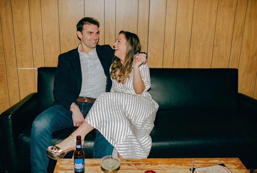 Engaged woman laughs with her fiancé in Boston bar