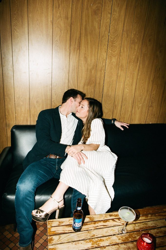 New England couple embraces in the couch in a vintage bar