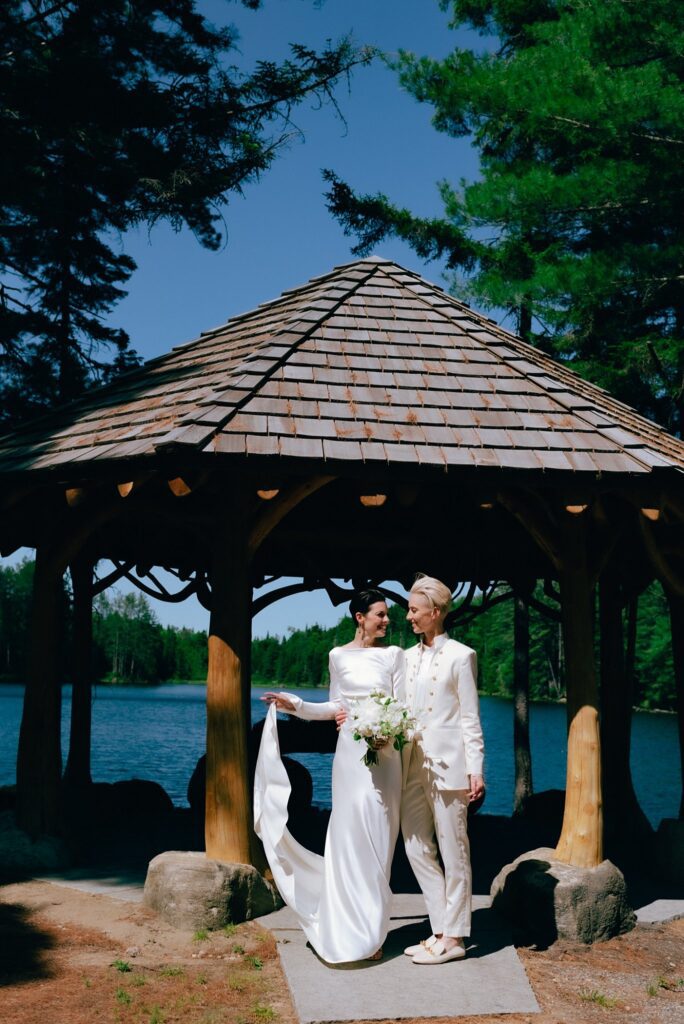 Film portrait of two brides posing in front of upstate New York lake