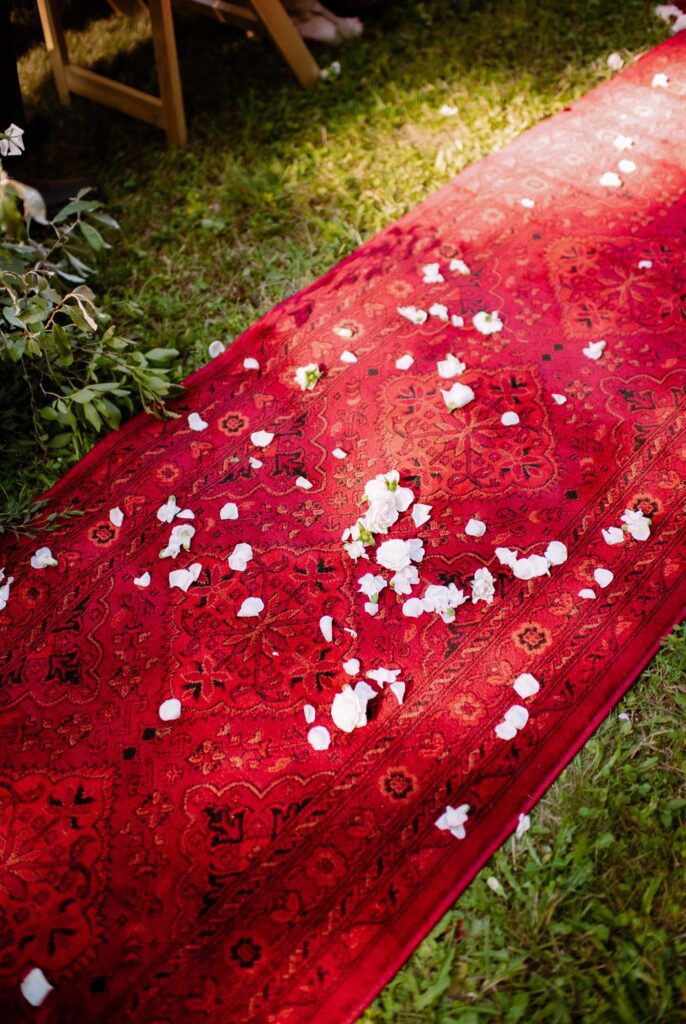 Flower petals adorn a runner carpet at bohemian upstate New York wedding
