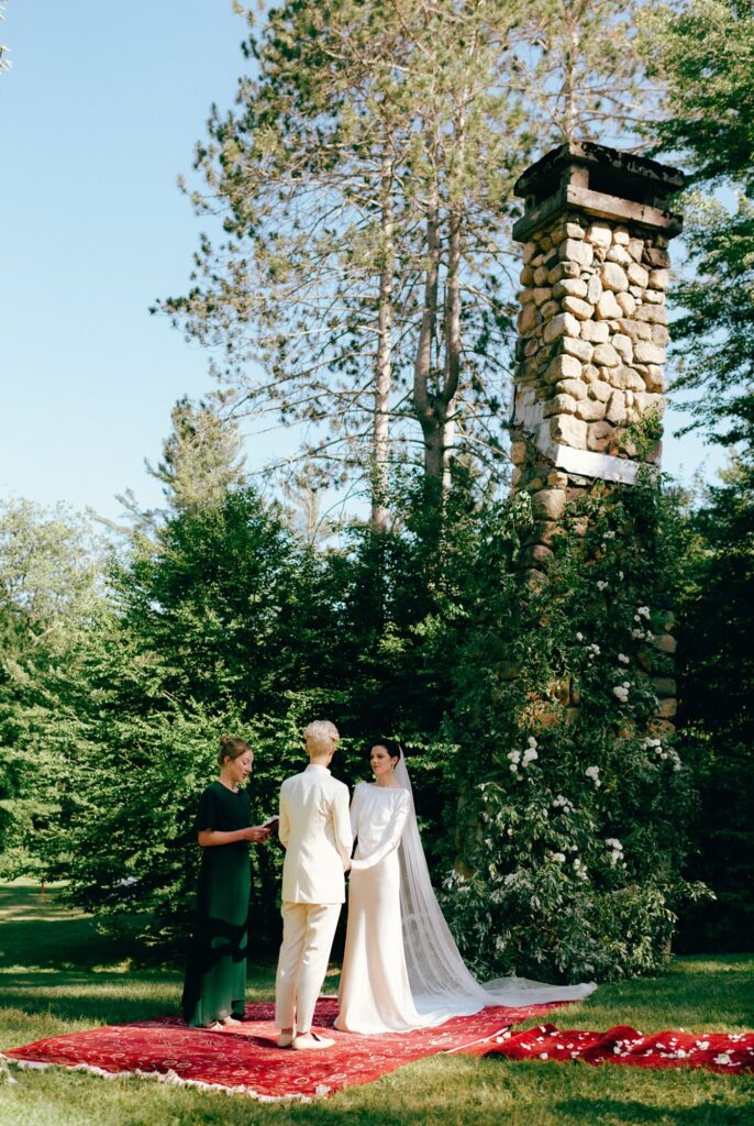 Trees and plants tower over two brides as they are wed in outdoor ceremony in the Adirondacks