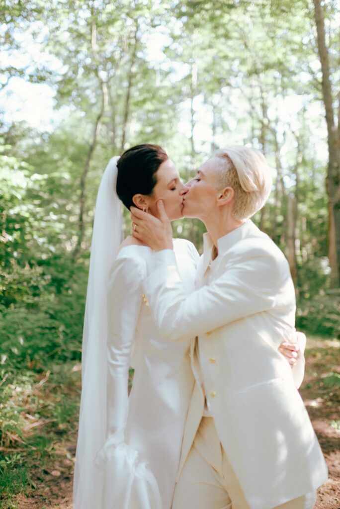Brides embrace and kiss amid Adirondacks woods