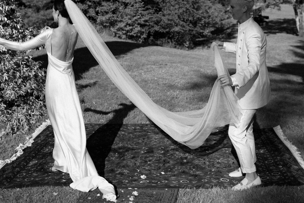 Black and white photo of bride holder her partner's veil
