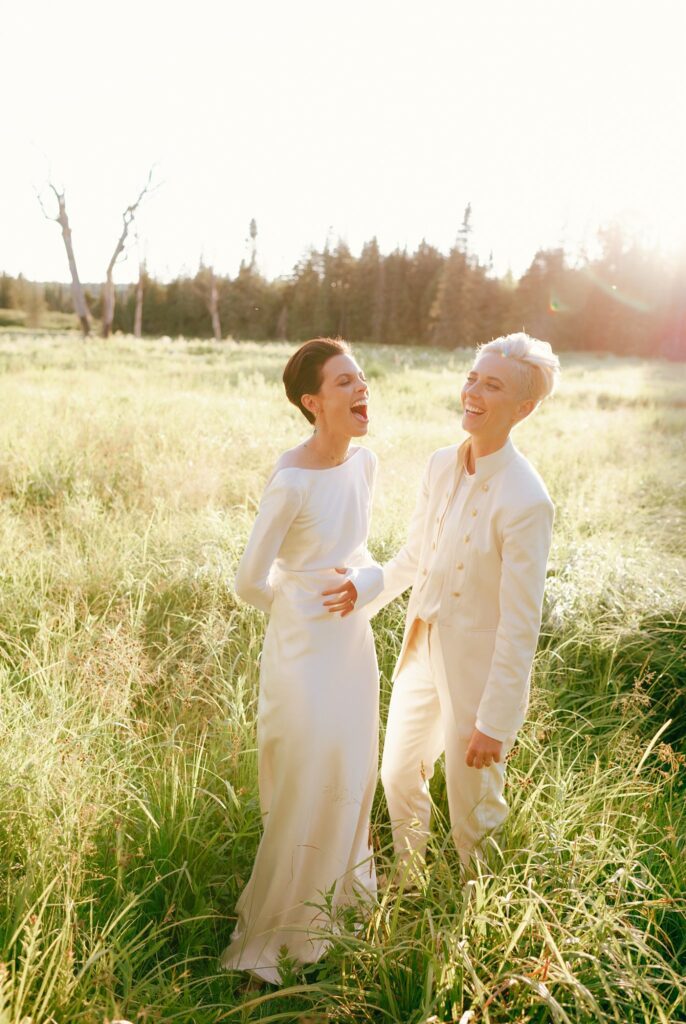 Brides laugh together at sunset at their upstate New York wedding