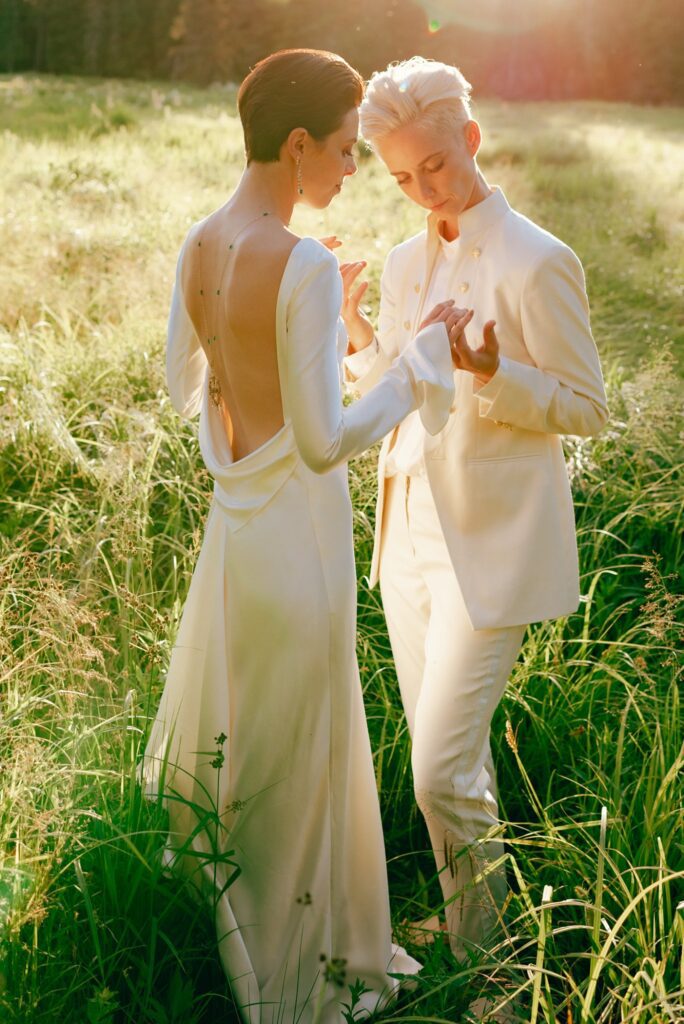 Brides hold hands in sun soaked field, captured on film