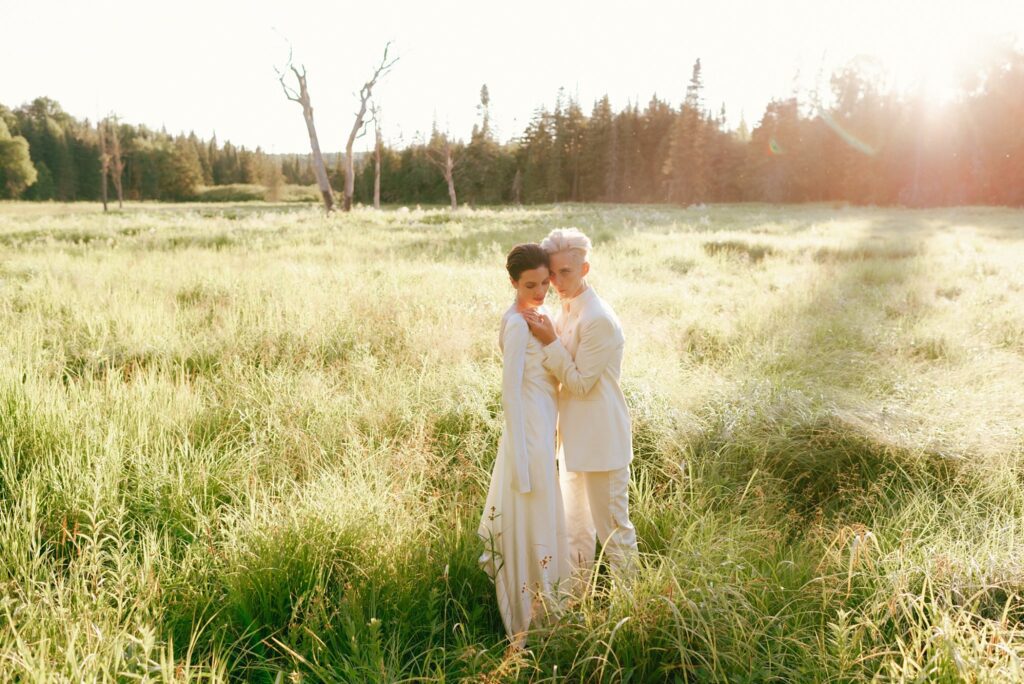 Brides embrace in field at sunset in the Adirondacks