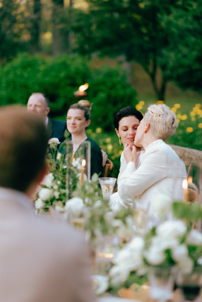 Brides kiss at their wedding dinner