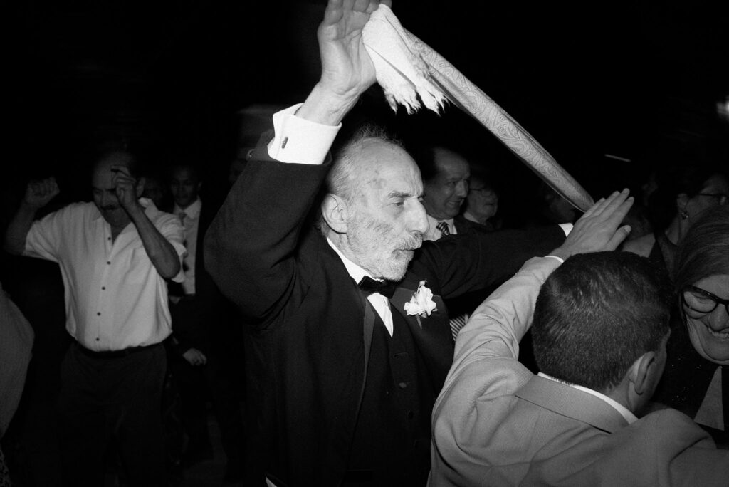 Black and white direct flash photo of wedding guests dancing