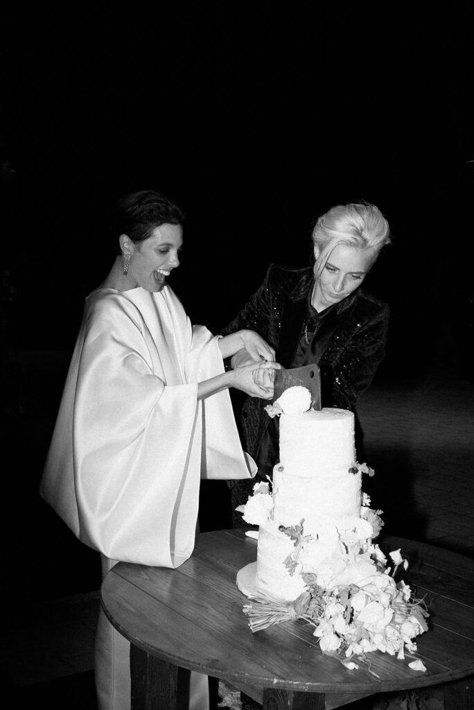 Black and white portrait of brides cutting cake