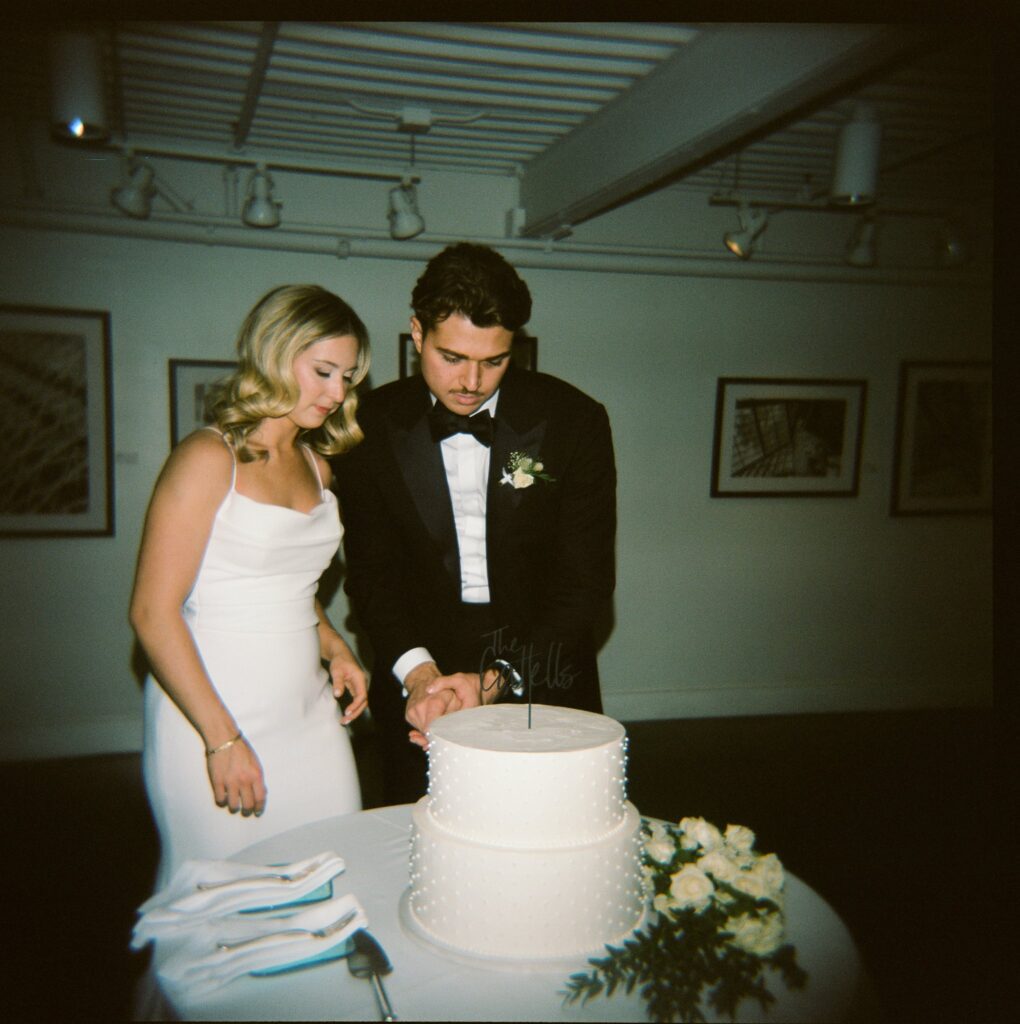 Film photo of newlyweds cutting cake at Artists for Humanity reception